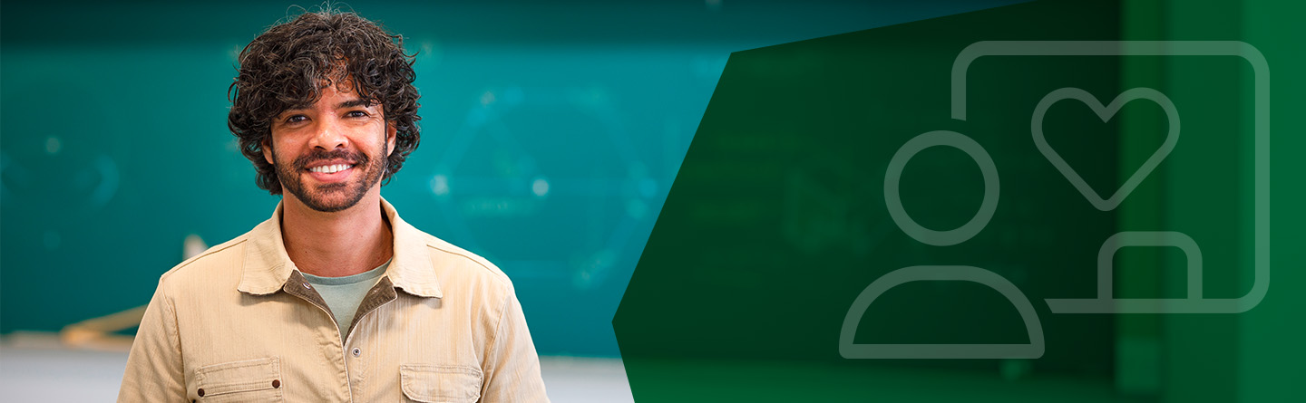 Header: Ein Mann lächelt in die Kamera. Im Hintergrund ist eine Tafel zu sehen.