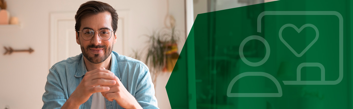 Header: Ein Mann mit Brille sitzt an einem Tisch und lächelt in die Kamera.