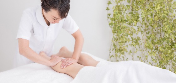 Kachelbild: Eine Physiotherapeutin massiert die Waden eines Patienten