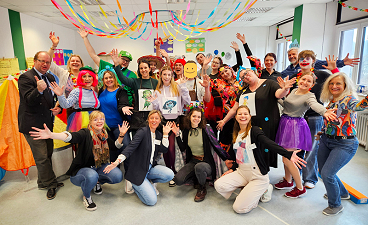 Gruppenbild: Schülerinnen und Schüler in bunter Faschingskleidung mit Lehrkräften am Tag der offenen Tür. 