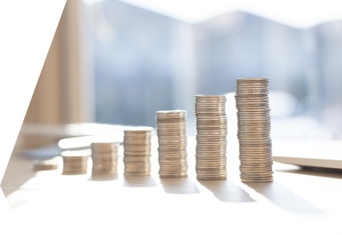 Stapel an Geldstücken auf einem Tisch; die Stapel werden von links nach rechts höher